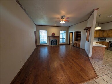 Unfurnished living room featuring ornamental molding, light wood-style flooring, ceiling fan, and a tiled fireplace