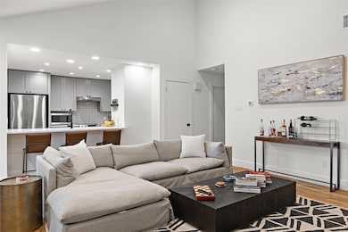 Living area featuring high vaulted ceiling, light wood-type flooring, and recessed lighting