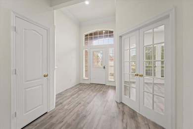 Entryway with light wood-style floors, crown molding, french doors, and a high ceiling