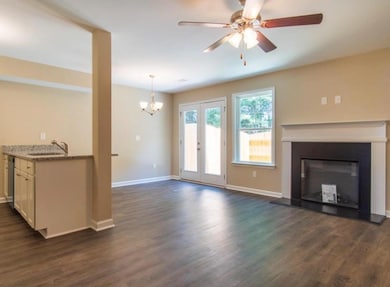 Unfurnished living room with a chandelier, dark wood-type flooring, ceiling fan, and a glass covered fireplace