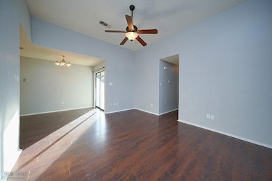 Unfurnished room with ceiling fan with notable chandelier, dark hardwood / wood-style flooring, and a textured ceiling