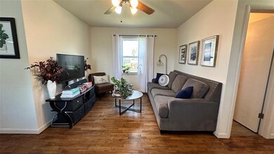 Living room featuring ceiling fan and dark hardwoo