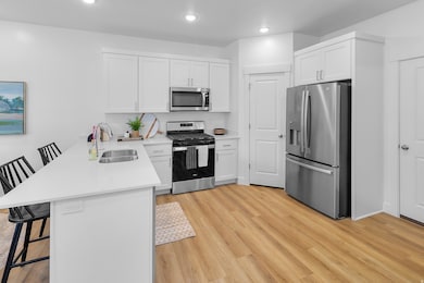 Kitchen featuring a breakfast bar, appliances with stainless steel finishes, a peninsula, white cabinets, and recessed lighting
