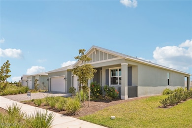 View of front of property with a front yard, stucco siding, a garage, driveway, and covered porch