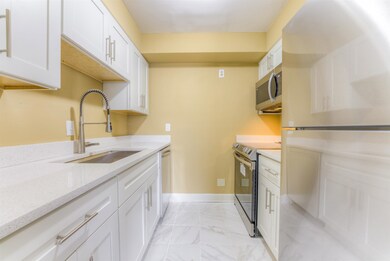 Kitchen featuring white cabinets, light stone coun
