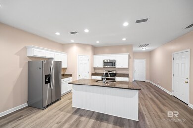 Kitchen featuring white cabinetry, sink, a center island with sink, and stainless steel appliances