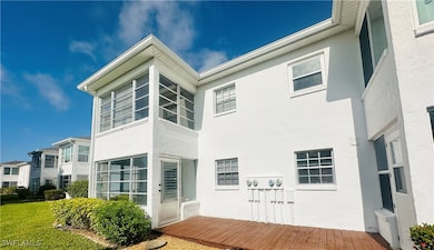 Back of property with stucco siding, a lawn, deck and private entry door.
