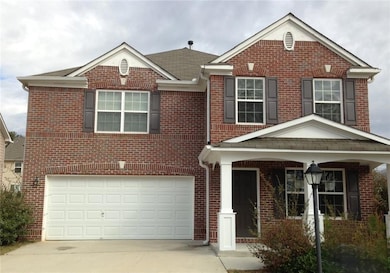 Traditional-style home with brick siding, a garage, concrete driveway, and a porch