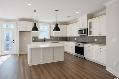 Kitchen featuring stainless steel appliances, tasteful backsplash, decorative light fixtures, white cabinetry, and recessed lighting