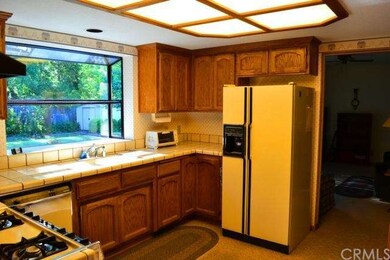 Open kitchen with oak cabinetry and tile counters,