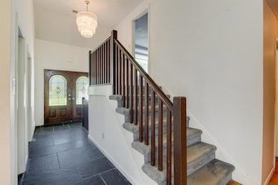 Tiled entryway with a notable chandelier