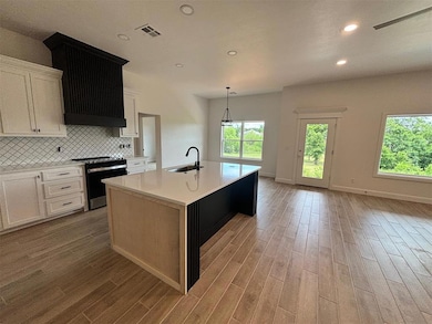 Kitchen featuring a center island with sink, range