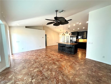 Kitchen featuring ceiling fan, dark cabinets, a si
