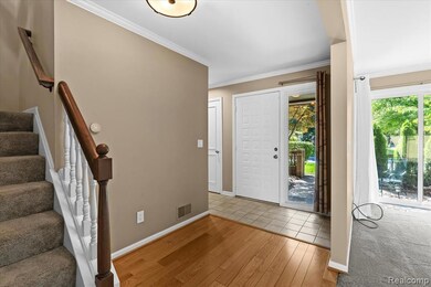 Entrance foyer with wood finished floors, crown molding, and stairway