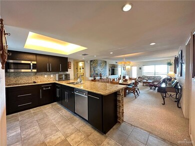 Kitchen featuring light carpet, sink, stainless steel appliances, a notable chandelier, and kitchen peninsula