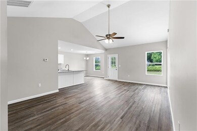 Unfurnished living room with ceiling fan, dark wood-style flooring, high vaulted ceiling, and a chandelier