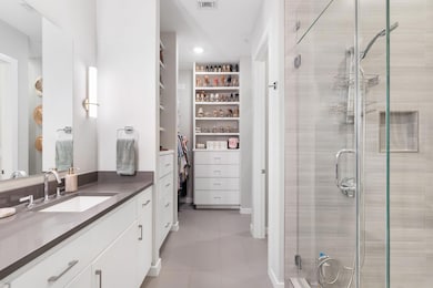 Bathroom featuring vanity, a shower stall, light tile patterned flooring, and a spacious closet