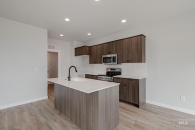 Kitchen featuring modern cabinets, tasteful backsplash, a kitchen island with sink, appliances with stainless steel finishes, and recessed lighting