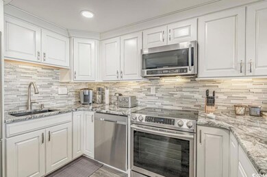 Kitchen with white cabinets, stainless steel appliances, light stone counters, tasteful backsplash, and recessed lighting