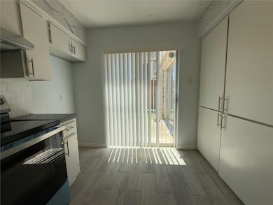 Eating kitchen with doors that lead to the backyard and plenty of cabinet space