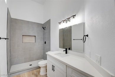 Full bath with a tile shower, vanity, and wood fin
