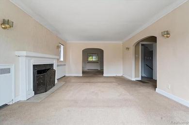 Unfurnished living room with crown molding, carpet flooring, radiator, a tiled fireplace, and arched walkways