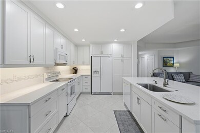 Kitchen with white appliances, white cabinets, light stone countertops, recessed lighting, and backsplash