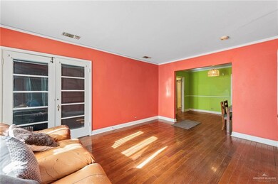 Living area featuring baseboards, hardwood / wood-style flooring, and ornamental molding