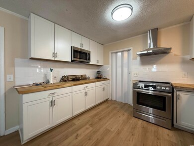 Kitchen featuring a textured ceiling, white cabine