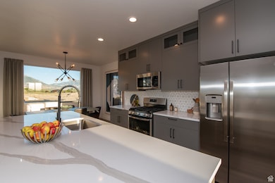 Pics are of model home.Kitchen with an inviting chandelier, sink, tasteful backsplash, decorative light fixtures, and stainless steel appliances