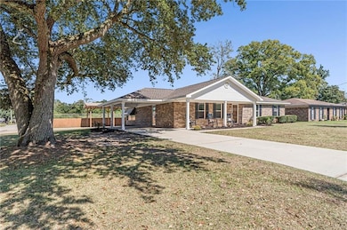Ranch-style house featuring a porch, concrete driveway, brick siding, and a carport