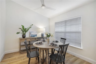 Dining area with light wood-style floors, baseboards, a ceiling fan, and vaulted ceiling