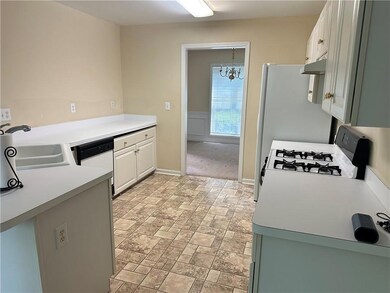 Kitchen with a sink, a chandelier, white appliances, under cabinet range hood, and white cabinetry