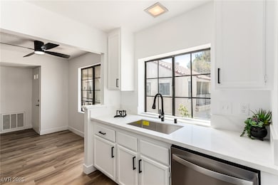 Kitchen featuring dishwasher, plenty of natural light, and white cabinetry