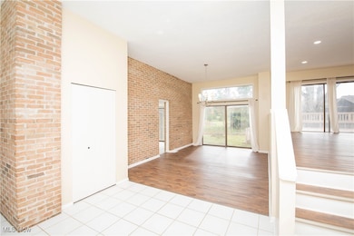 Entrance foyer featuring light tile patterned floors, brick wall, a chandelier, and recessed lighting