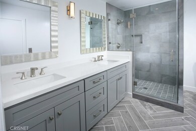 Sumptuous master bathroom with a new state-of-the-art vanity with quartz counter-tops, new His and Her undermount dual basins, new faucets, new dual framed dressing mirrors, new designer lighting, new frameless glass enclosed custom tiled step-in sho