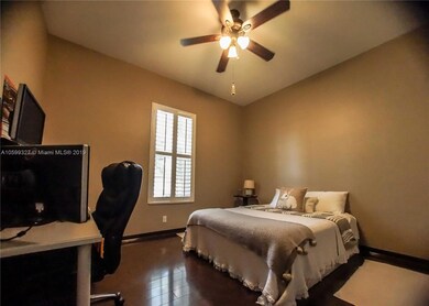 First Bedroom with Walnut Piano-Finished Laminate Flooring and Plantation Shutters.