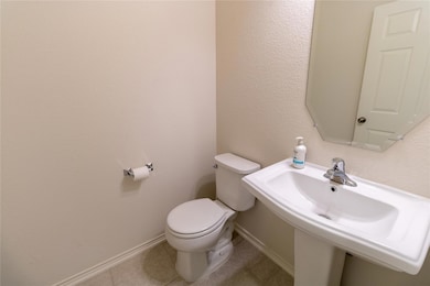 Bathroom with toilet, tile patterned floors, a si