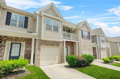 View of front of property featuring a balcony, a garage, concrete driveway, and brick siding