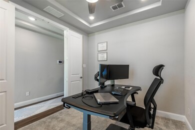 Home office with ceiling fan, a tray ceiling, and wood-type flooring