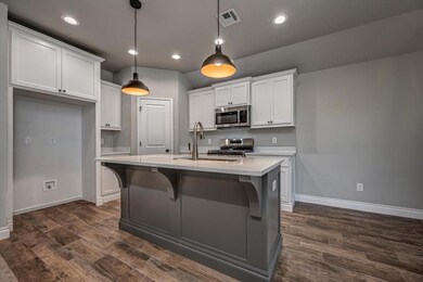 Kitchen with appliances with stainless steel finishes, a sink, baseboards, dark wood-style floors, and recessed lighting