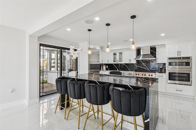 Kitchen featuring backsplash, glass insert cabinets, a kitchen breakfast bar, pendant lighting, and stainless steel appliances