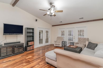 Living room featuring french doors, hardwood / wood-style floors, lofted ceiling with beams, and ceiling fan