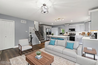 Living room featuring dark wood-style flooring and stairs