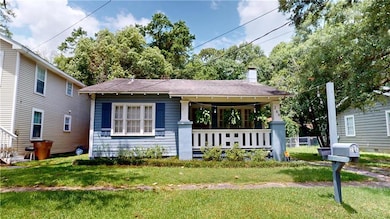 View of front of property with a front lawn, covered porch, roof with shingles, and a chimney