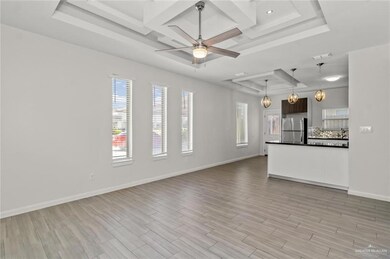 Unfurnished living room featuring light hardwood / wood-style flooring, a tray ceiling, ceiling fan, and coffered ceiling