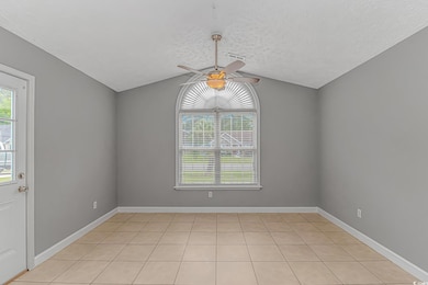 Empty room featuring a ceiling fan, lofted ceiling