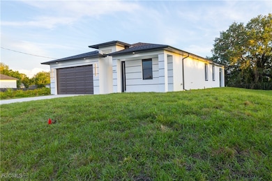 View of front of house with an attached garage, a front lawn, driveway, and stucco siding