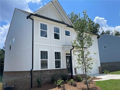 Modern farmhouse style home with board and batten siding, brick siding, driveway, and an attached garage