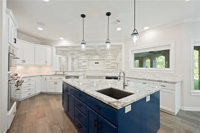 Kitchen featuring an island with sink, light wood-